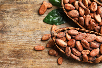 Cocoa pods and beans on wooden table, above view with space for text
