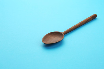 Clean empty wooden spoon on blue background, space for text