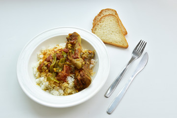Chicken curry with rice on a white plate on a white background. Top view.