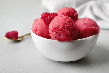 Delicious pink ice cream with raspberries in bowl on grey table