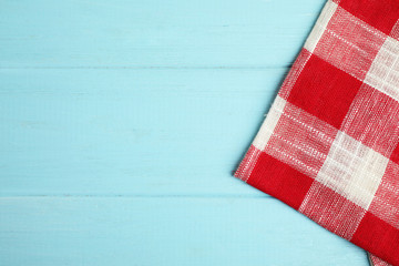 Red plaid kitchen towel on light blue wooden background, top view. Space for text