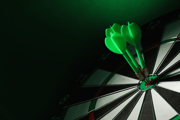 Color arrows hitting target on dart board against green background. Space for text