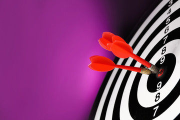 Red arrows hitting target on dart board against purple background
