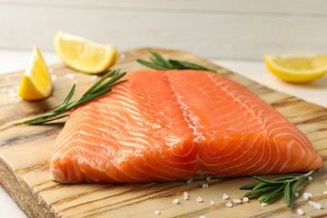 Fresh salmon fillet with rosemary and salt on wooden board, closeup
