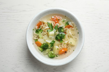 Bowl of fresh homemade vegetable soup on white wooden background, top view