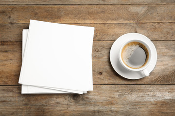 Blank paper sheets for brochure and cup of coffee on wooden background, flat lay. Mock up
