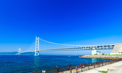 [兵庫県の風景] 明石海峡大橋と淡路島を望む瀬戸内海の岸壁で早朝から家族で釣糸を垂らす釣り人達