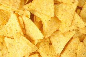 Tasty Mexican nachos chips as background, top view