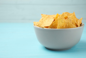 Bowl of tasty Mexican nachos chips on light blue table