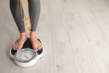 Woman with tape standing on scales indoors, space for text. Overweight problem - obrazy, fototapety, plakaty
