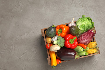 Crate with different fresh vegetables on grey background, top view. Space for text