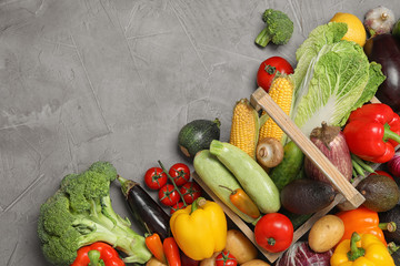Many different ripe vegetables and basket on grey background, flat lay. Space for text