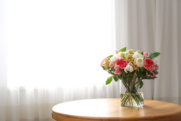 Beautiful flower bouquet in vase on table near window at home. Space for text