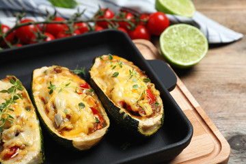 Baked stuffed zucchinis on wooden table, closeup
