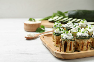 Tasty stuffed zucchini rolls on white wooden table. Space for text