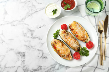 Baked stuffed zucchinis served with sauces on white marble table, flat lay. Space for text