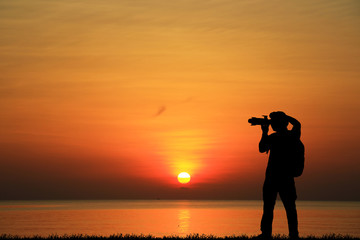 Silhouette of photographer with his camera on sunrise