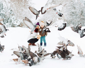 Mother and her son, winter walk, posing and some pigeons flying in front