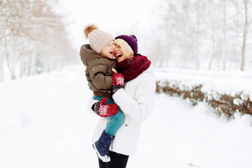 Fototapeta na wymiar Photo of mother and son, havinf fun, hugging and laughting in a winter walk