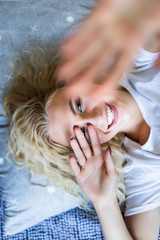 Beautiful girl making selfie in the bed. Beautiful girl making self on the bed at home. Selfie in the morning. Beautiful young woman making selfie while standing in front of window