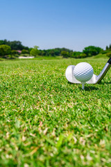 Golf Ball on tee with iron golf club. Golf course with a rich green turf beautiful scenery.