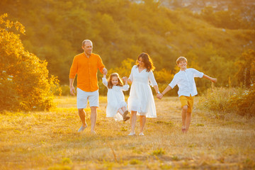 Photo of a family, walking in afield, and holding hands, enjoying the time