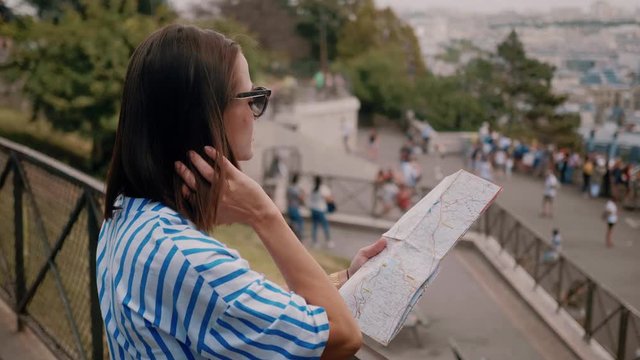 Young woman in Paris checks destinations on the map