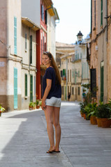 Obraz na płótnie Canvas Junge schöne Frau in einer Häuser-Gasse der Altstadt Alcudia Mallorca Spanien Shopping Sight Seeing 