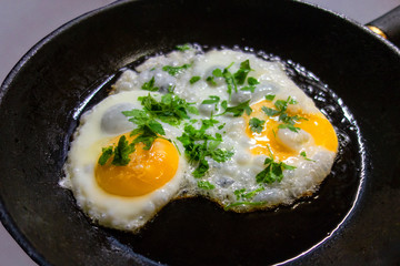 Sunny side up fried eggs with parsley decoration on cast iron frying pan. Concept of home made...
