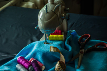  Sewing machine at work, scribble fabric on the background of a meter, scissors and threads - obrazy, fototapety, plakaty