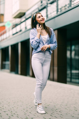 Cheerful brunette woman talking on the phone in the street