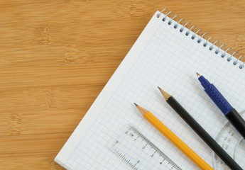 Office supplies on notepad on wooden background
