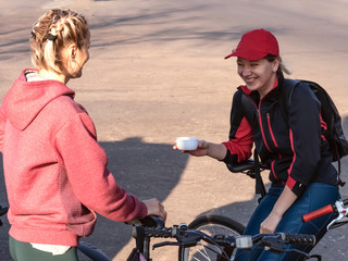 Two young girls in sportswear are resting after a bike ride. They drink tea, laugh and talk.