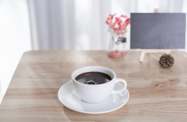 coffee cup and black board  on office table with white curtain background in morning light