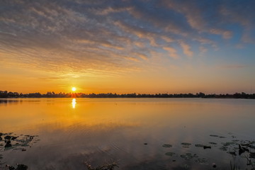 Lake view morning of yellow sun light and cloudy sky background, sunrise at Krajub reservoir, Ban Pong District, Ratchaburi, Thailand.