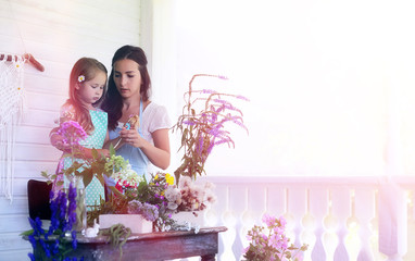 A young girl with a daughter is picking up a bouquet. A young mother with her daughter makes a...