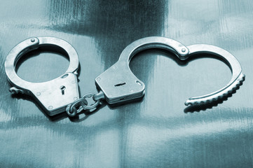 Steel metallic handcuffs on wooden table
