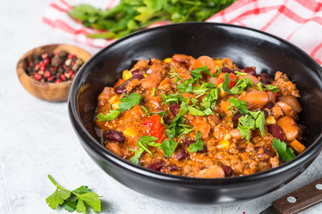 Chili con carne from meat and vegetables on stone table close up.