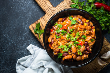 Chili con carne from meat and vegetables on black table top view