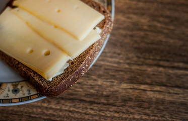 Bread with butter and cheese on it on the plate with wooden background
