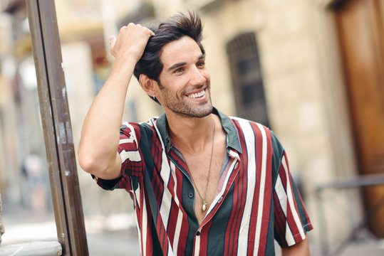 Smiling young man touching his hair wearing casual clothes outdoors