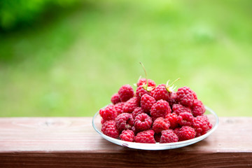 Raspberry berries on a wooden table. Summer mood. A treat. Green background.