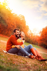 Romantic couple relaxing on grass in autumn park