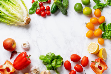 Overhead image with healthy cooking ingredients on marble surface with copy space. Vegetarian cooking concept. Tomatoes, salad, basil and peppers.