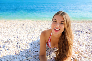 Happy beautiful smiling girl enjoying relax lying on the beach looking at camera. Summer holidays concept. Copy space.