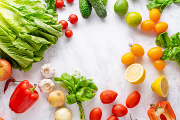 Overhead image with healthy cooking ingredients on marble surface with copy space. Vegetarian cooking concept. Tomatoes, salad, basil and peppers.