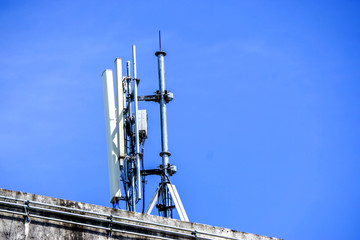 Devices and Receivers Communication Signal with antennas on the top of building and bright blue sky background.