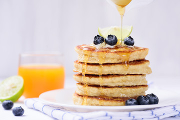 Pouring honey on oatmeal pancake with blueberry