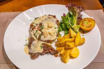 Beef steak with creamy sauce and roasted potatoes in restaurant