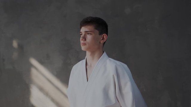 High minded, prideful young taekwondo warrior get ready for the call or fight. Confident boy looks into the lens. Camera moves and zoom in to face. Taekwondo traditional arts